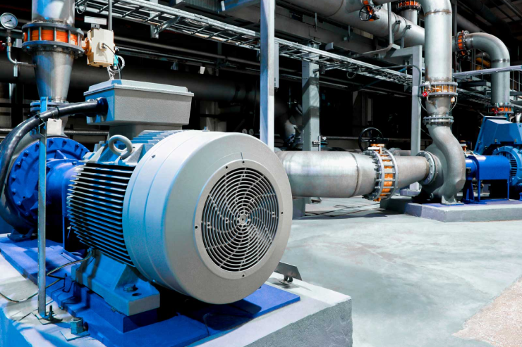 Industrial machinery setup with large metal pumps and pipes in a bright, clean factory setting. The blue and silver tones convey an efficient, modern atmosphere.